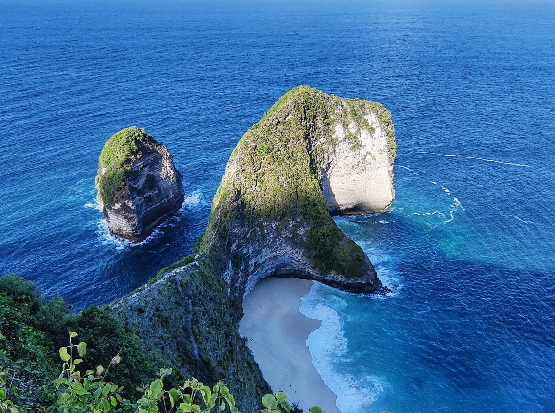 Vue spectaculaire sur la plage de Kelingking, où d’imposantes falaises plongent dans l’océan bleu de Nusa Penida